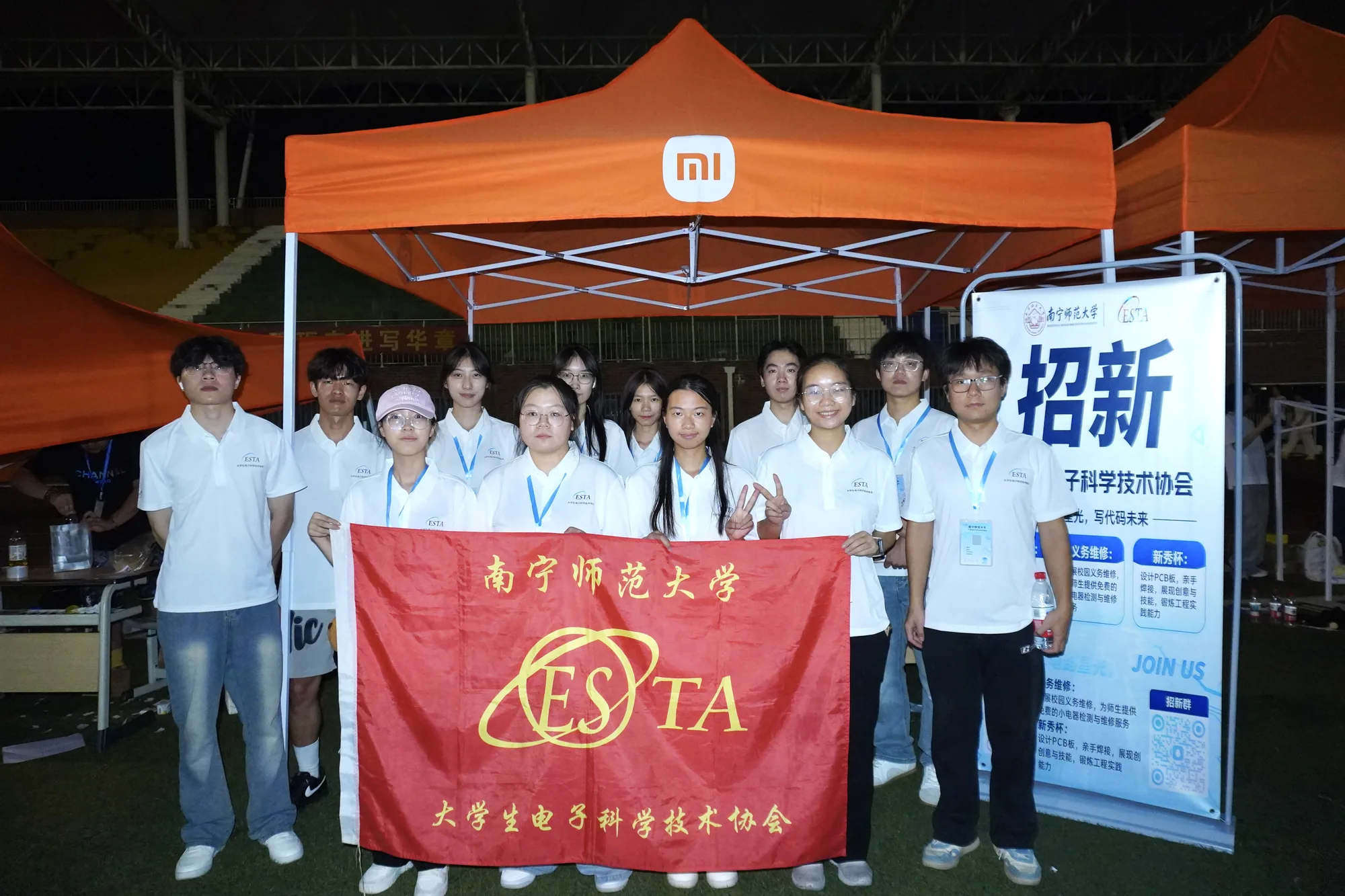招新摊位前，社团成员举着 ESTA 旗帜合影