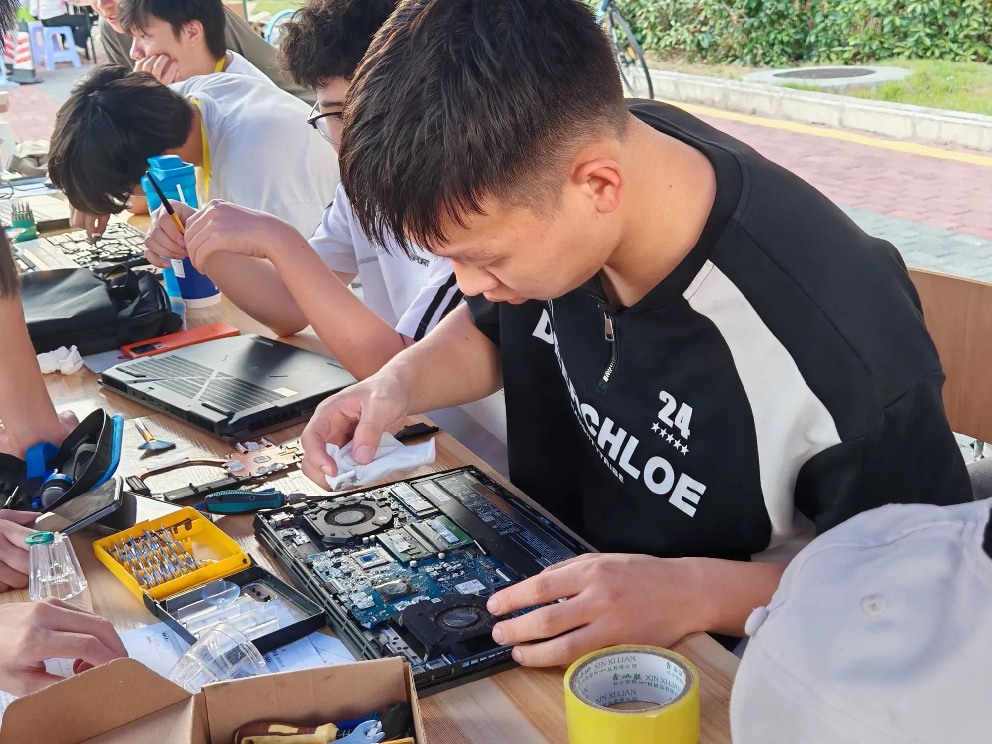 义务维修现场，学生在工作台上检查电子设备